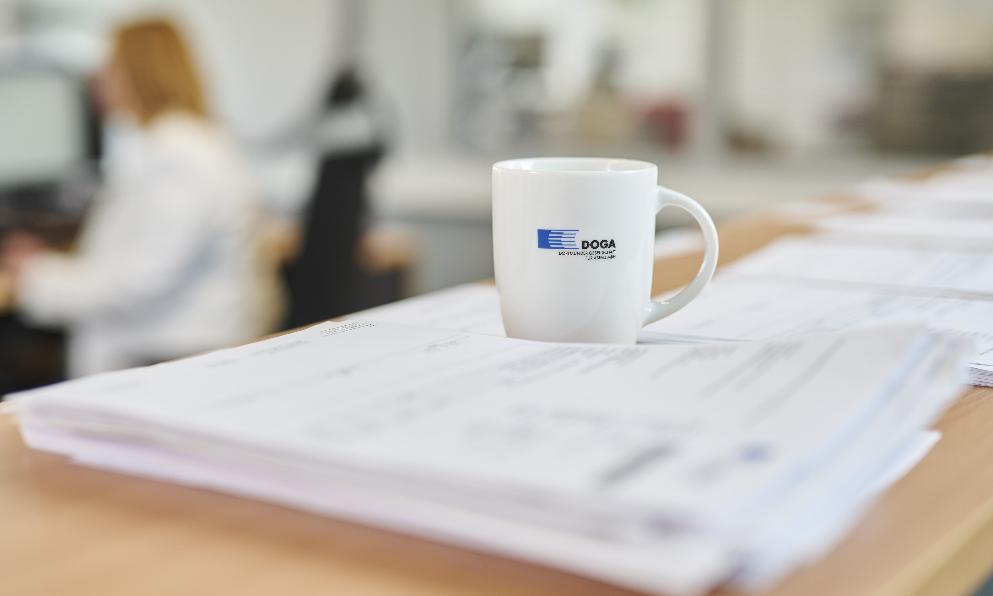 Eine weiße Tasse mit einem DOGA Aufdruck auf einer weichgezeichneten Zeitung